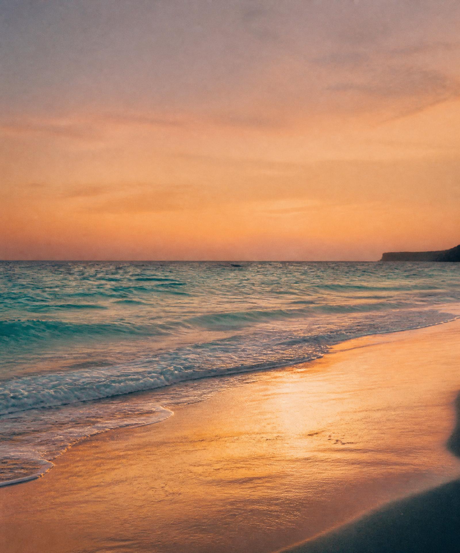 Mar turquesa encontrando areia dourada ao pôr do sol